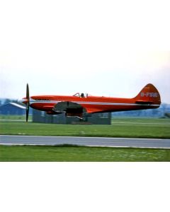 Red vintage aircraft with registration G-FIRE taking off on a runway, showcasing its unique design against a grassy landscape.