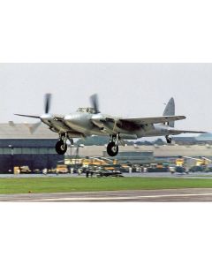 Vintage Silver Mosquito aircraft taking off from an airfield, showcasing its distinctive twin-engine design and propellers.