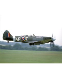A vintage military aircraft, a Supermarine Spitfire, flying over a green landscape, featuring a dark green body with distinctive roundel markings and "APOD" painted on the side.