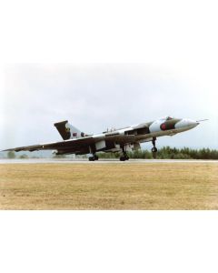 Vulcan bomber taking off on a runway with green trees in the background.
