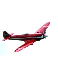 Vintage red aircraft flying against a white sky, showcasing its sleek design and vibrant colors.