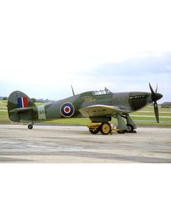 Supermarine Spitfire PZ865 on the tarmac, showcasing its distinctive green and grey camouflage with a roundel and "The Last of the Many!" inscription.