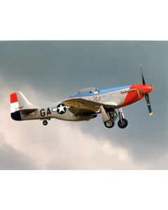 P-51 Mustang fighter aircraft in flight, showcasing a silver and red color scheme with military insignia against a cloudy sky.