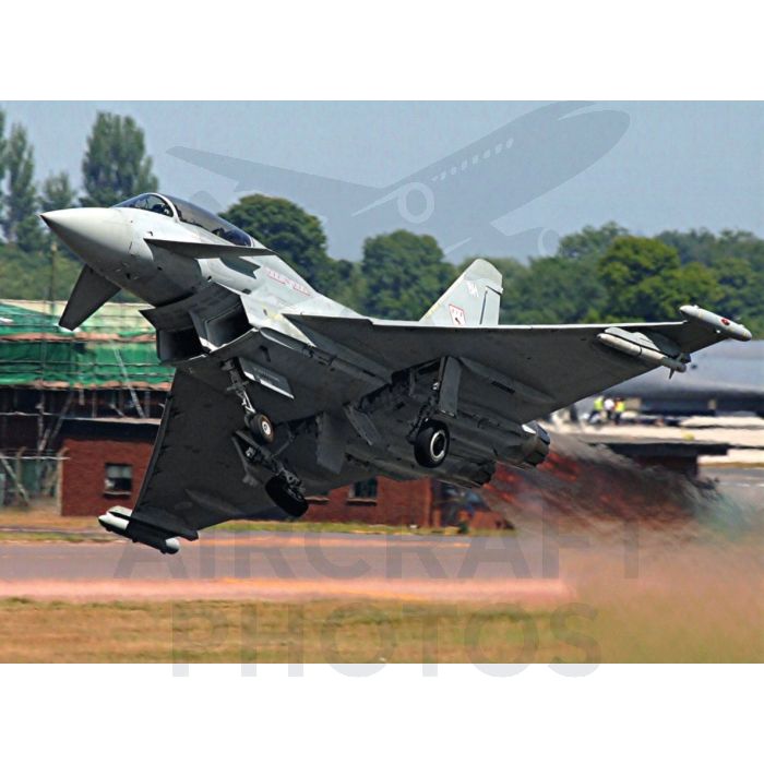 Eurofighter Typhoon jet taking off with smoke trail on a runway.