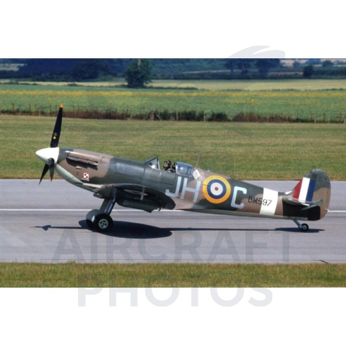 Vintage Supermarine Spitfire aircraft on the runway, featuring a camouflaged design, British roundel, and a clear sky background.