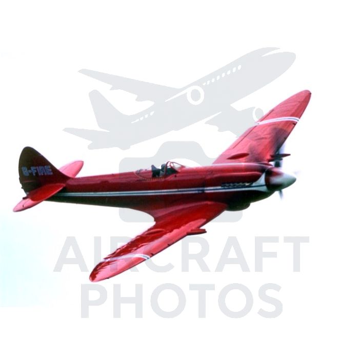 Vintage red aircraft flying against a white sky, showcasing its sleek design and vibrant colors.