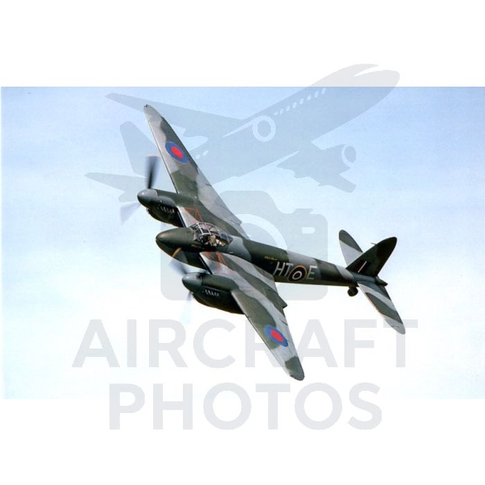 A vintage fighter plane flying against a clear blue sky, displaying a camouflage pattern and roundels on its wings.