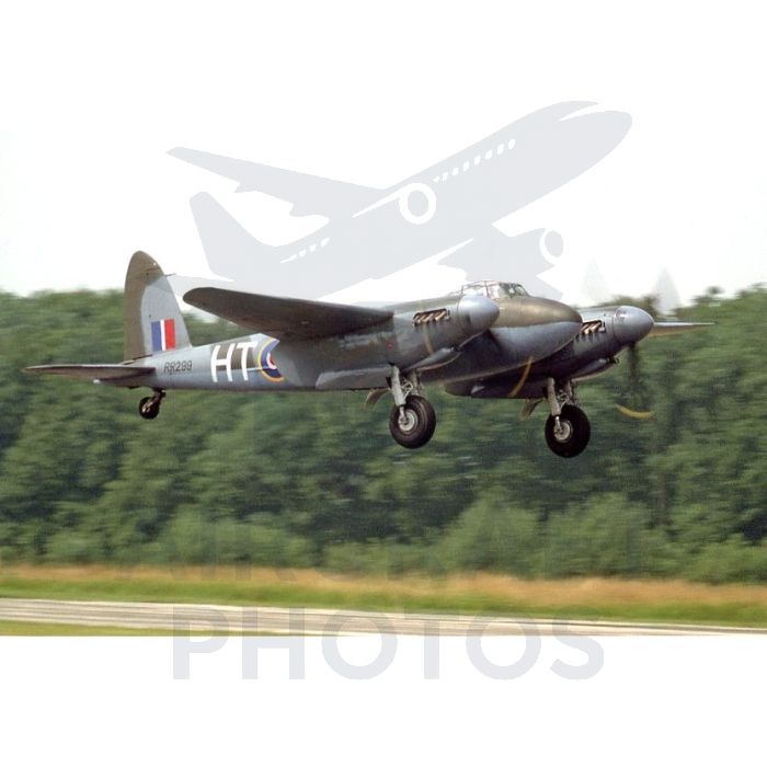 A vintage aircraft, possibly a de Havilland Mosquito, taking off against a lush green backdrop, showcasing its distinctive twin-engine design and military markings.