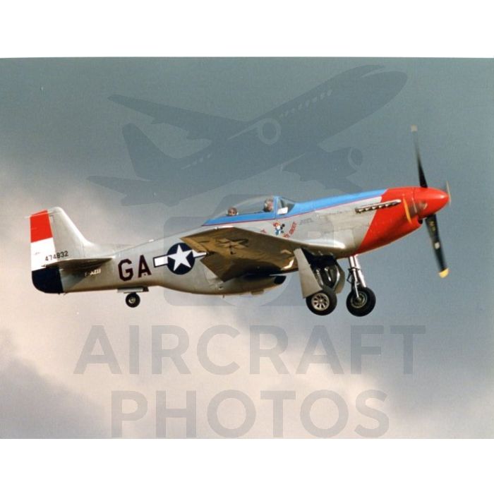 P-51 Mustang fighter aircraft in flight, showcasing a silver and red color scheme with military insignia against a cloudy sky.